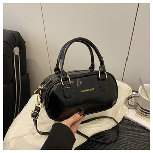 Close-up of black patent leather bowling bag with gold zippers and metal hardware