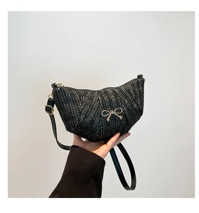 Close-up of black woven crescent bag featuring a delicate gold metal bow and zipper