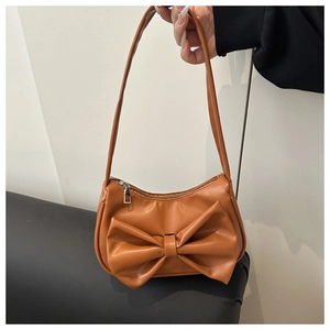 Détail d'un sac à main en cuir PU caramel avec grand nœud décoratif et zip argenté