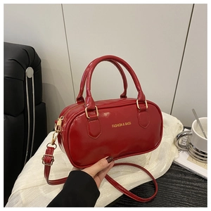Detail of red patent leather mini Boston bag with gold zippers and adjustable strap
