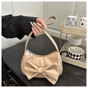 Détail du sac hobo avec un grand nœud décoratif et une finition en cuir PU beige lisse