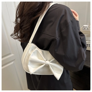 Détail d'un sac à main blanc en cuir PU avec un grand nœud décoratif porté par un mannequin