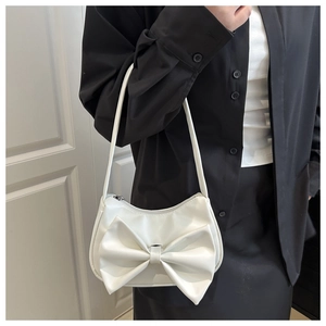 Detail view of the elegant white underarm bag featuring a large decorative bow on the side