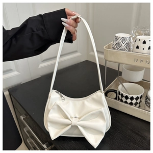 Détail de la décoration avec un grand nœud sur le sac à main blanc en cuir avec fermeture