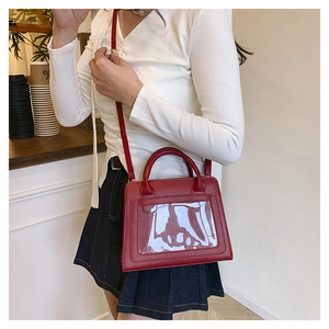 Detail der roten PU-Lederhandtasche mit transparentem Sichtfenster und Schultergurt
