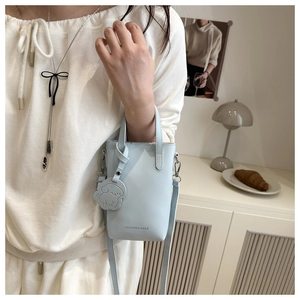 Detail of light blue mini crossbody bag with cute dog charm and silver-tone hardware