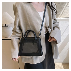 Detail view of black leather crossbody square bag with transparent window and gold hardware