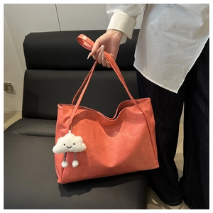 Detailansicht der korallenrosa Leder-Tote-Bag mit einem süßen weißen Wolken-Plüschanhänger