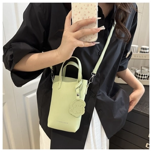 Detail of pistachio green mini handbag with puppy charm and adjustable crossbody strap