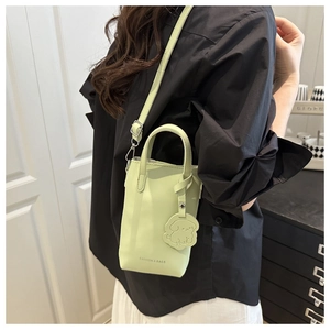 Detail shot of light green mini bucket bag with fashion text and cute dog charm ornament