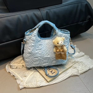 Light blue ruched fabric bucket bag with teddy bear pendant and adjustable strap