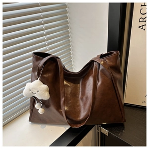 Gros plan du sac cabas vintage marron foncé en similicuir avec un pendentif nuage blanc