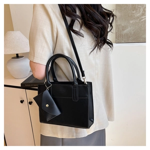 Detailed view of a black square tote bag with elegant side-hanging mini envelope pouch