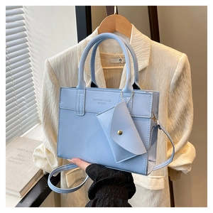 Detail of light blue leather tote bag with FASHION & BAGS print and mini pouch