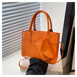 Detailed view of orange pebbled leather tote set with small pouch and gold hardware