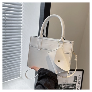 White leather tote bag with embossed text detail and detachable triangular charm pouch