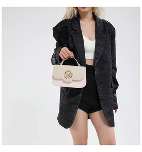 Detail of beige crossbody bag featuring herringbone weave flap and golden M logo buckle