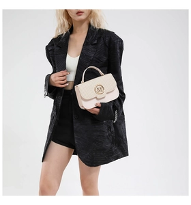 Detail of beige crossbody bag featuring herringbone texture and gold M buckle