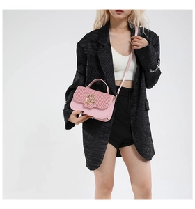 Pink crossbody bag featuring herringbone pattern and golden M buckle on stylish leather