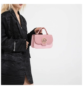 Detail of pink crossbody bag with woven V-pattern flap and gold M logo buckle on suit