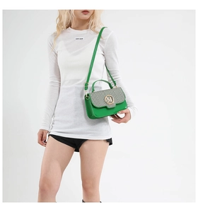 Detail view of the green leather handbag featuring a striped flap and gold M-logo buckle