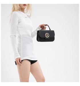 Detail of black textured leather handbag featuring a golden M-shaped metal buckle on the flap