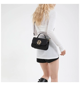 Close-up of black leather crossbody bag with golden M logo on a female model