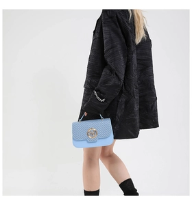 Detail of light blue crossbody bag with V-weave pattern and golden M-logo clasp