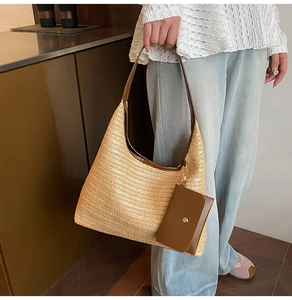 Close-up of straw woven hobo bag featuring brown leather trim and small purse charm
