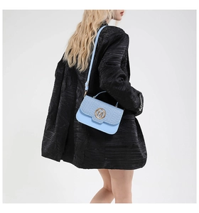 Model showcasing a light blue woven bag with a gold M logo and black blazer