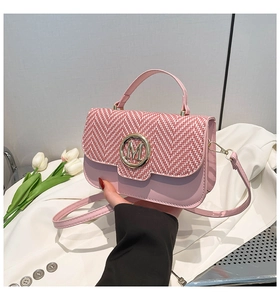 Detail of pink herringbone weave mini bag with golden M buckle and fresh tulips