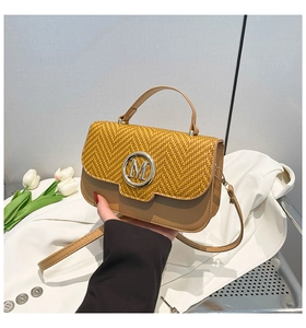 Detail of the herringbone texture and leather finish with a silver M-logo on a stylish handbag