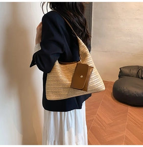 Detail of hand-woven straw tote bag with detachable brown leather pouch and metal buckle