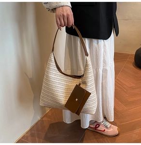 Detail of woven straw tote bag with brown leather handles and matching small pouch charm