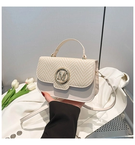 Detail view of woven leather crossbody bag with golden M logo and top handle