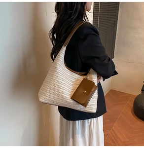 Detail of cream straw tote bag featuring brown leather straps and a small flap pouch charm