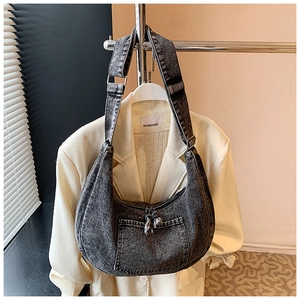 Detailed texture of dark grey washed denim crescent bag with adjustable wide strap