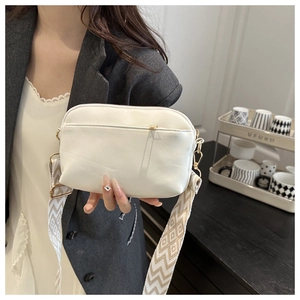 Close-up of white crossbody bag with geometric ethnic embroidery wide strap and gold hardware