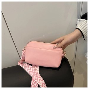 Detailed view of pink crossbody bag with wide geometric woven strap and gold hardware