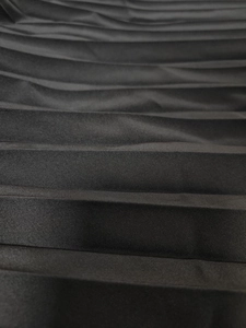 Makroansicht der feinen Textur von eleganten schwarzen Akkordeonfalten an einem Modekleid