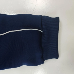 Detail of navy blue ribbed cuffs with white piping on a comfortable knit tracksuit