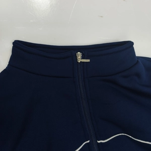 Detail of dark blue zip-up jacket with stand-up collar and white striped hem decoration