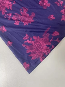 Detailed macro view of deep purple fabric with pink floral print and stitched hemline