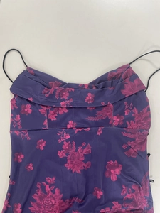 Detail of a purple floral slip dress with pink blossoms, ruched neckline and thin straps