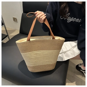 Macro detail of natural straw woven tote bag with brown gradient stripes and fabric handles