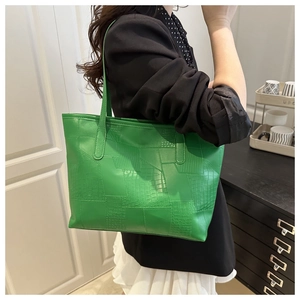 Close-up of green tote bag with geometric faux crocodile texture and long shoulder straps