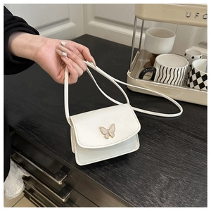 Detail of white leather mini square bag featuring a delicate metal butterfly buckle