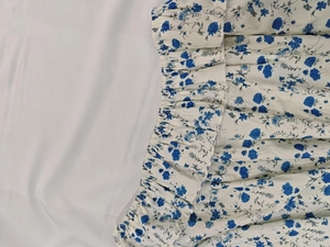 Vue détaillée du motif floral bleu et de la taille élastique à volants sur tissu blanc