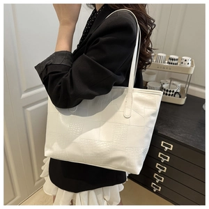 Detail of white large capacity tote bag featuring elegant crocodile texture and long shoulder strap