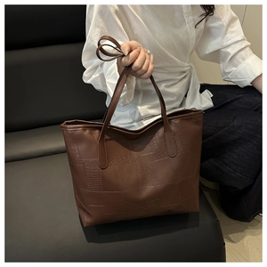 Detailed macro view of dark brown tote bag with crocodile pattern and patchwork design